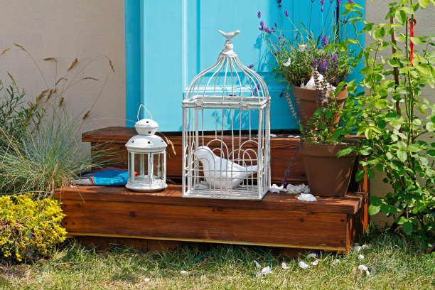 门口台阶上立着装饰用的瓷鸟笼，花盆里放着烛台和鲜花图片下载