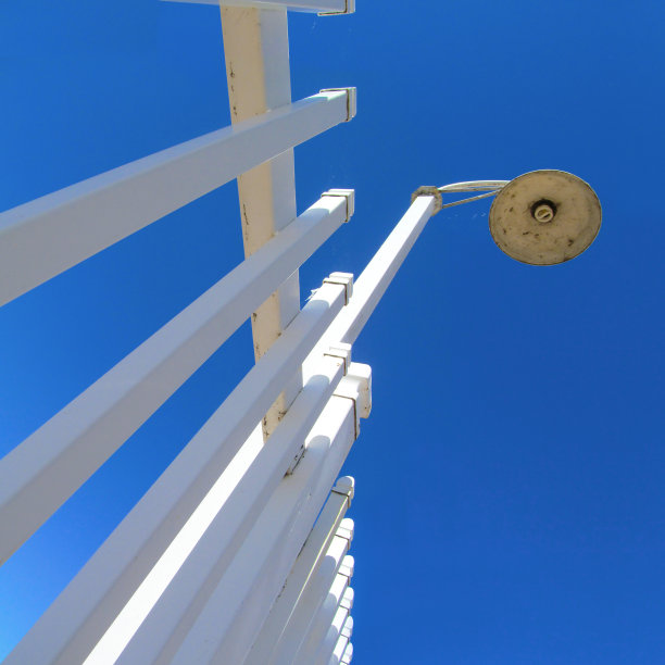 蓝色的天空映衬着白色的篱笆和路灯。图片下载