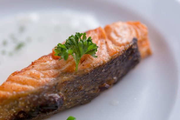 餐厅里的白盘子里放着加了白酱的鲑鱼排图片下载