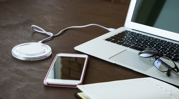 商务洽谈构图美观时尚。装有一堵砖墙的室内时尚木桌上摆放着可以无线充电的钢制笔记本电脑、平板电脑和智能手机。图片下载