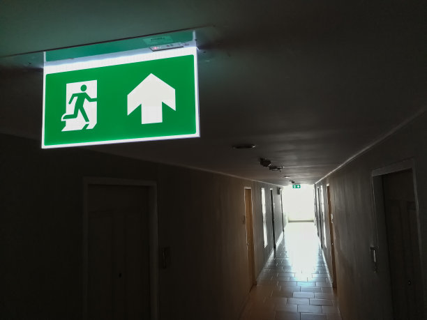 大楼的防火梯，公寓。一个相当黑暗的走廊和消防出口标志灯使其可见。与复制空间的文本图片下载