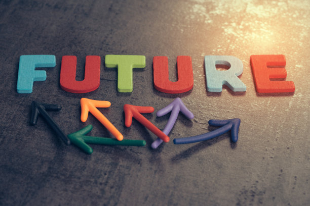 不确定的未来为人生旅程的概念，彩色的木制字母排列词未来与多向箭头在深色的黑色黑板墙上与金色的光，风险或恐惧图片下载