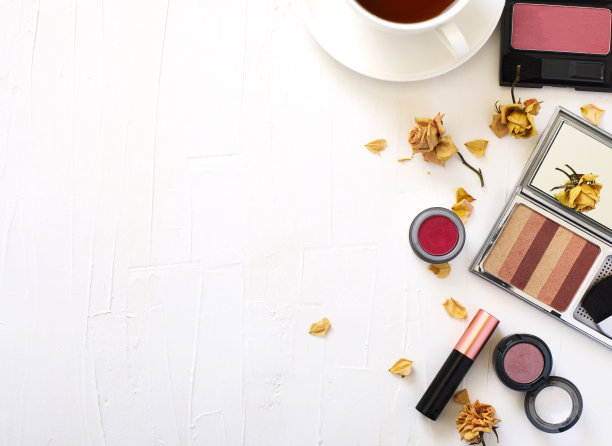 在白色的背景上平躺着一杯茶和女性化妆产品图片下载