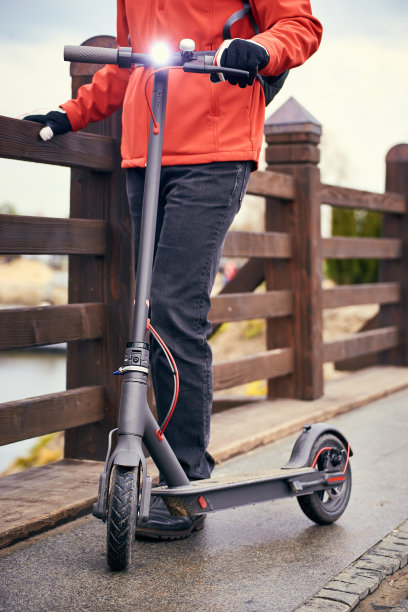 一个穿着红色夹克背着背包骑摩托车的男人在街上。图片下载