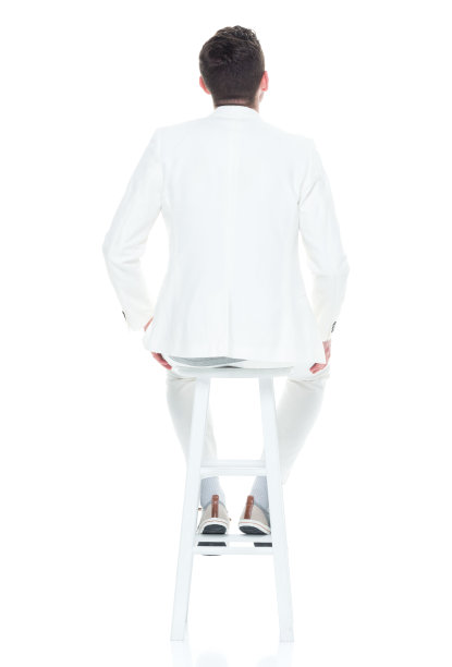 英俊的年轻人坐在凳子上白色西装后视图图片下载