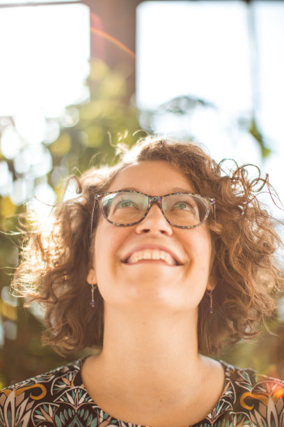 真正的年轻女子在阳光下微笑。低头笑着。温室和农业图片下载