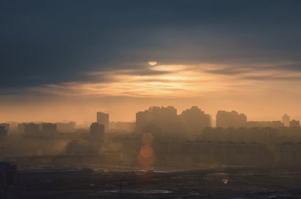 城市景观剪影与一盘阳光透过低云层的污染的城市大气。图片下载