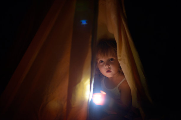 夜色中，盖着罩子的女孩手里拿着一盏小灯素材图片