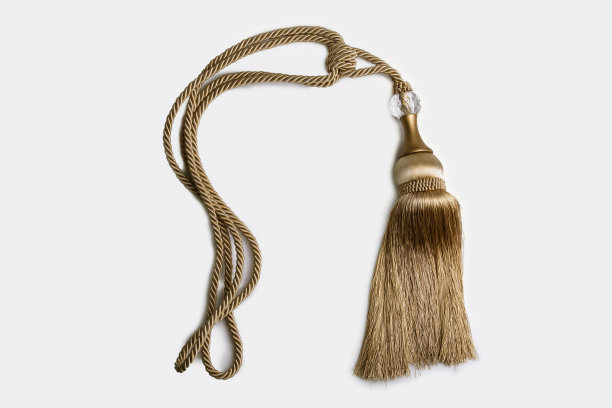 白色背景中金色装饰流苏结与编织绳的特写镜头图片下载