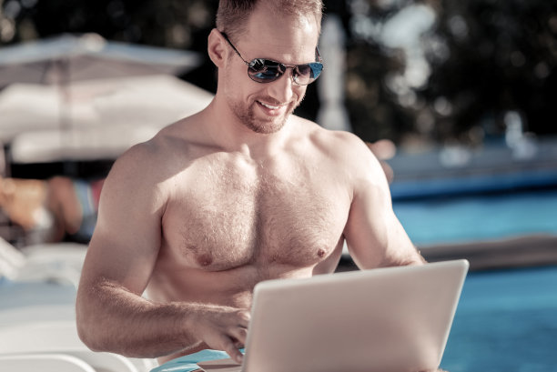 酷酷的年轻人在户外使用笔记本电脑时喜气洋洋图片下载