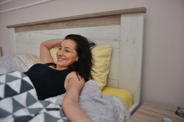 快乐的年轻女子在床上醒来图片下载