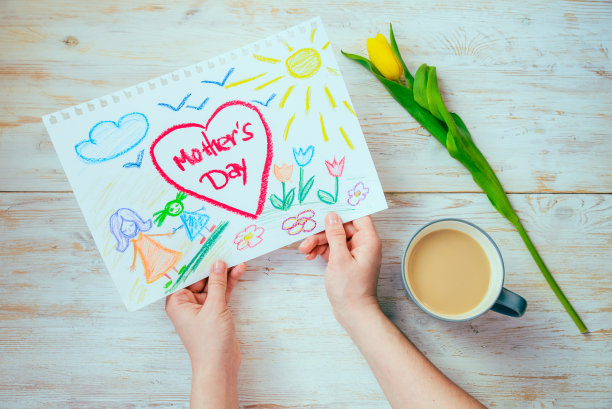 妈妈一边喝咖啡一边看着孩子的照片和母亲节祝贺。俯视图片下载