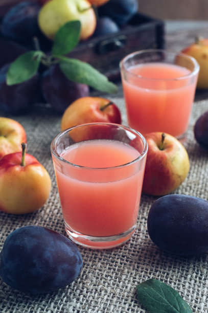 新鲜梅子汁。杯子里的果汁配上新鲜的李子和小苹果放在亚麻布餐巾上图片下载