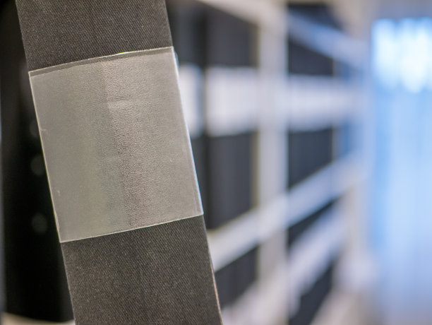 黑色活页夹在前景与一个空的标签和在背景模糊的架子活页夹。图片下载