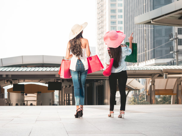 后视图的年轻女性购物袋享受购物，亚洲女孩有乐趣与他们的购买在城市。消费主义和生活方式观念图片下载