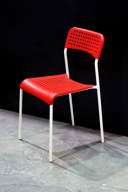 带有穿孔表面的红色金属椅子。一件时髦的家具。图片下载