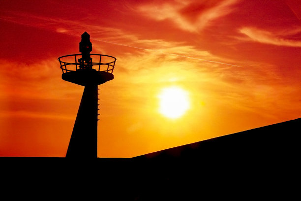 灯塔的剪影映衬着引人注目的红色天空。图片下载