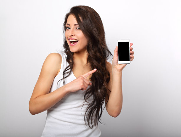 幸福的微笑美丽的化妆女人拿着和广告手机在白色的背景与空白的拷贝空间。特写肖像图片下载