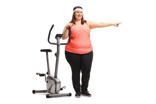 一个超重的女人靠在健身自行车上指着图片下载