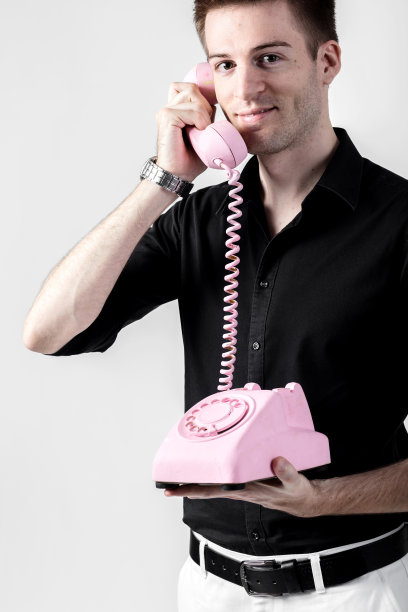 一个年轻男子的肖像，在一个白色背景的老式电话上交谈图片下载