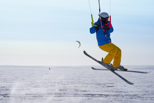 一个男运动员正在一个大的雪湖上的冰上放风筝。他跳起来。冬天晴朗有霜的一天。特写镜头。图片下载