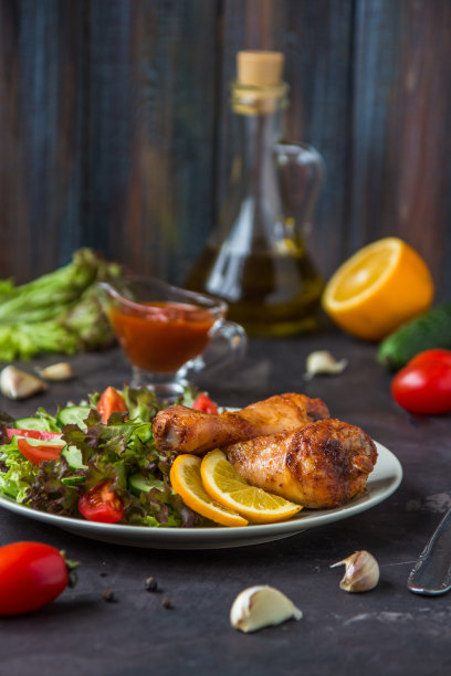 炸鸡腿和新鲜的沙拉在黑暗的背景图片下载