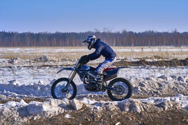 运动员、赛车手在极速公路上骑着摩托车飞驰。跑道很不平。晴朗有霜的冬日。图片下载