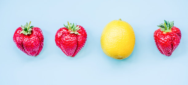 柠檬和三个草莓孤立在蓝色的背景图片下载