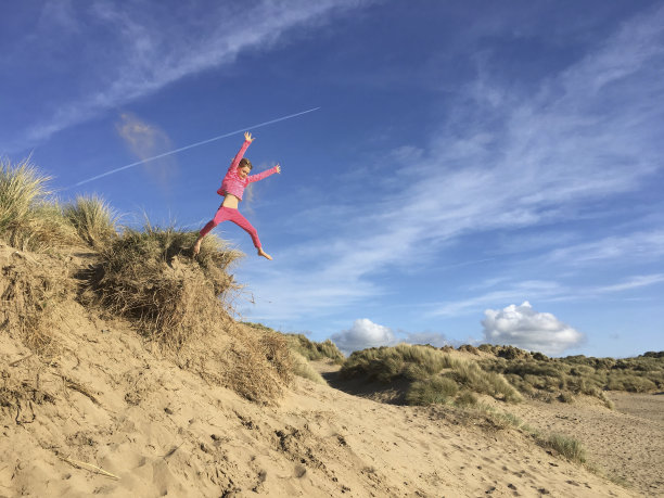半空中的年轻女孩从沙丘跳下来的肖像图片下载