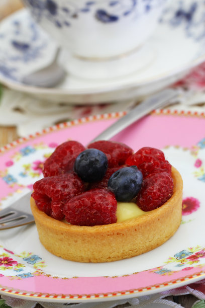 美味的塔利特配蛋奶沙司，新鲜的树莓和蓝莓放在粉红色的盘子里图片下载