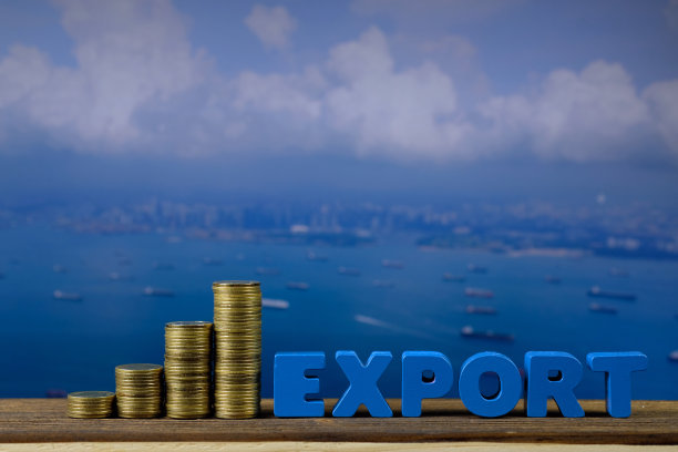 出口文字和硬币堆叠在木桌上，从空中俯瞰海景和货轮，进出口概念。素材图片