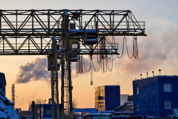 工业区。室外起重支架。黎明时分在露天仓库和装卸区上方的电动架空起重机。背景是一个正在抽烟的烟斗图片下载