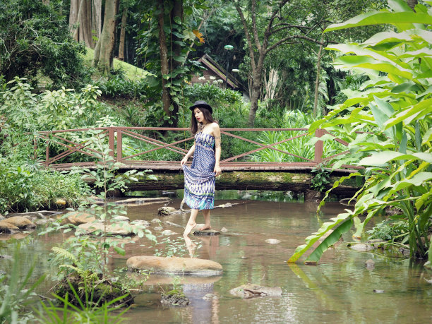 近距离拍摄的一个美丽的半种姓女士穿着蓝色裙子在小溪上摆姿势在Mae Hong Son省，泰国的森林。选择性聚焦，模糊前景和背景。图片下载