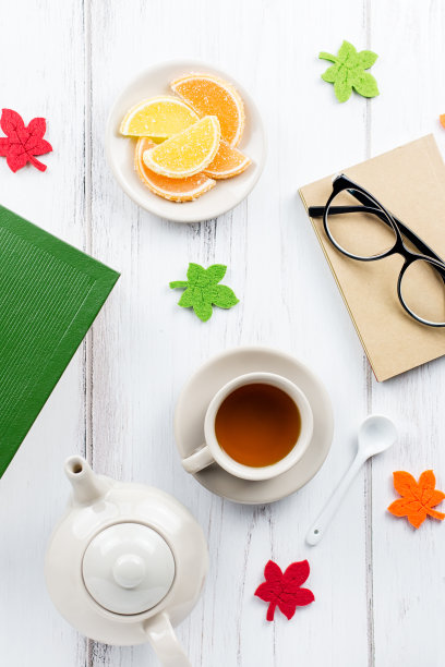 女性办公台平放着日记、眼镜、书、茶杯、糖果和毛毡装饰。图片下载