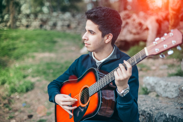 一个十几岁的男孩在大自然中弹吉他图片下载