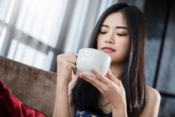 美丽的亚洲女人在白色衬衫放松和蛤与热饮与幸福时刻与白色窗帘背景图片下载