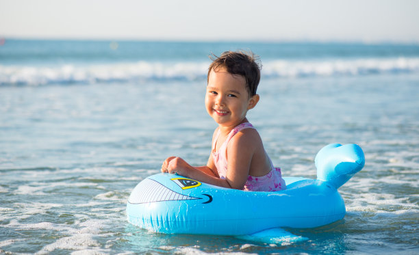 小女孩骑着充气艇在海里游泳图片下载