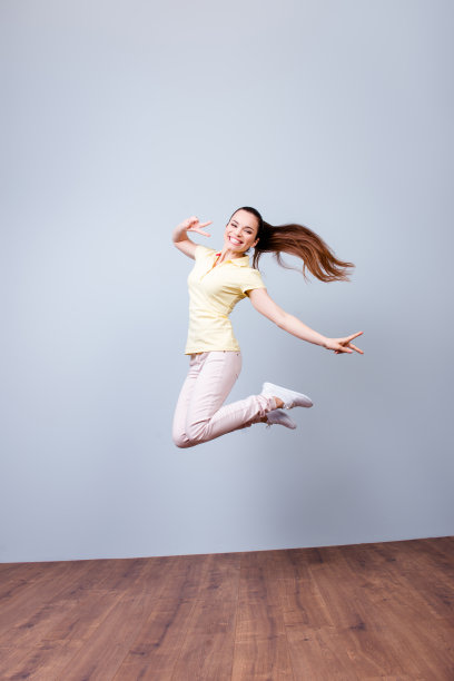 幸福、梦想、乐趣、快乐理念。非常兴奋快乐的女孩跳了起来，穿着休闲的衣服，打着和平的手势图片下载