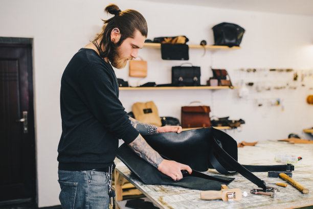 皮包车间的工作流程。漂流工具在工作台上的背景。图片下载