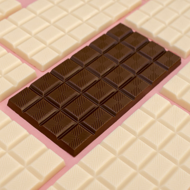 黑巧克力与白巧克力在粉红色的背景上排成一排图片下载