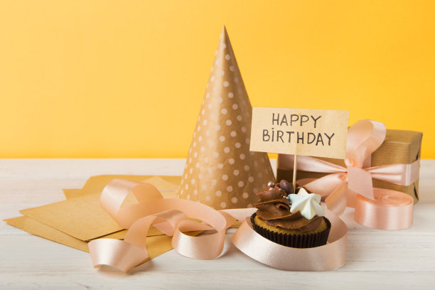 美味的纸杯蛋糕和黄色背景的礼物图片下载