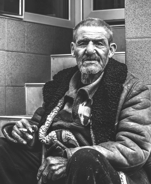 贫穷而无家可归的吉普赛老人坐在街头楼梯上抽烟向人们乞讨，社会纪录片概念，黑白垂直肖像图片下载