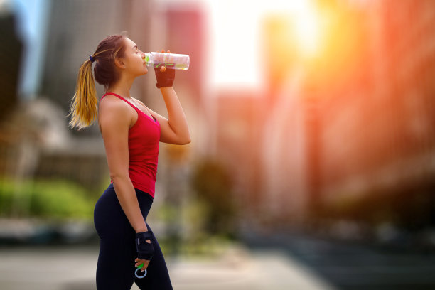 妇女在运动服装饮用水后，在城市景观锻炼图片下载