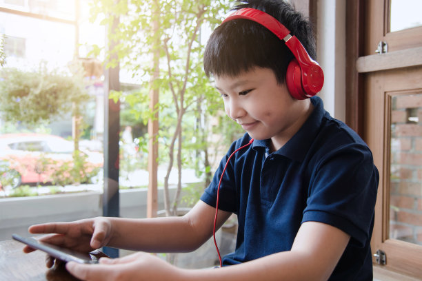 迷人的亚洲男孩在房间里用耳机听音乐。图片下载