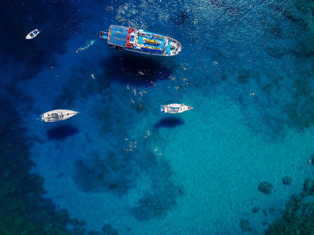 航拍美丽的蓝色泻湖在炎热的夏日与帆船。俯视图的人正在游船周围。图片下载