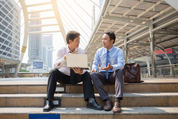 两个商人正在与智能手机和笔记本电脑的商业概念。图片下载