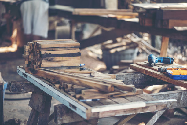 木工车间的背景图像:木工工作台与不同的工具和木材切割架，复古滤镜图像图片下载