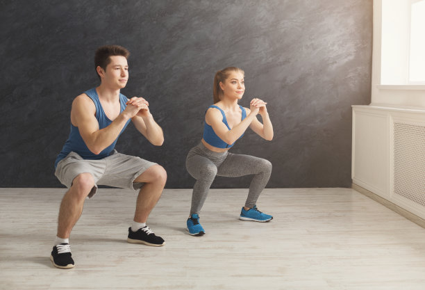 年轻夫妇穿着运动服做下蹲素材图片