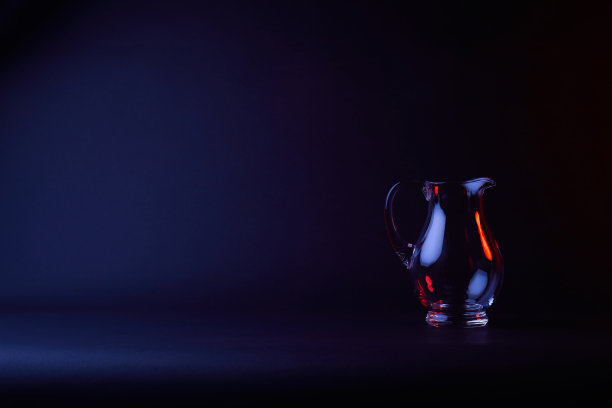 一个在黑暗的表面上反射的空玻璃花瓶图片下载