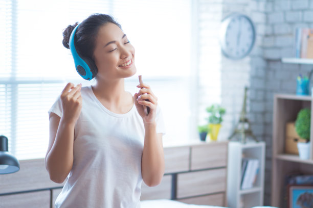 亚洲妇女正在听音乐，她在房间里唱歌。幸福的图片下载